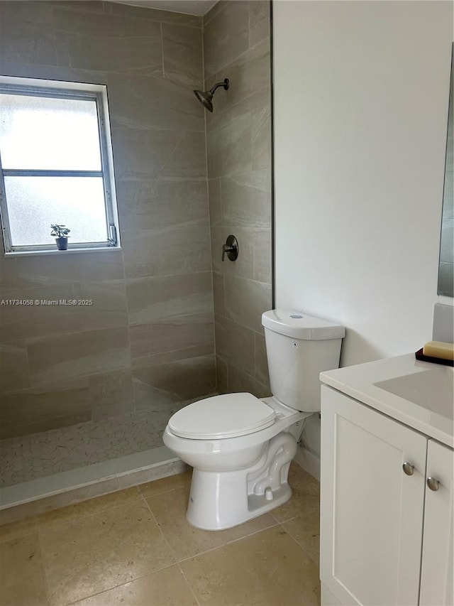 bathroom featuring vanity, a tile shower, and toilet