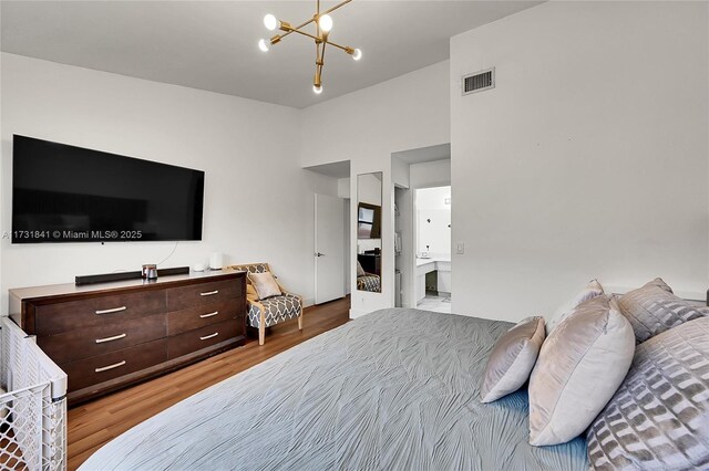 bedroom featuring an inviting chandelier, wood-type flooring, and vaulted ceiling