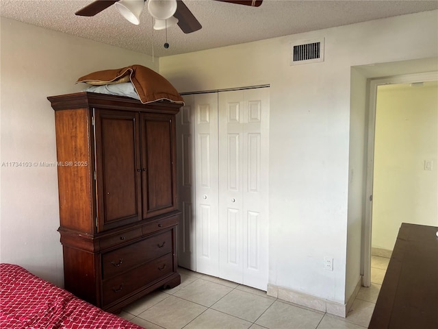 unfurnished bedroom featuring ceiling fan, a closet, a textured ceiling, and light tile patterned floors