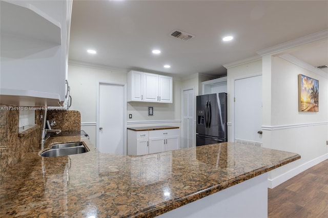 kitchen featuring white cabinetry, sink, dark stone counters, kitchen peninsula, and black refrigerator with ice dispenser