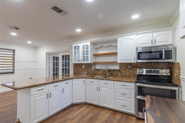 kitchen with sink, dark stone countertops, stainless steel appliances, white cabinets, and kitchen peninsula