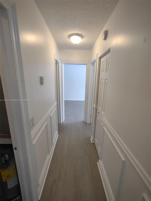 corridor with dark wood-type flooring and a textured ceiling