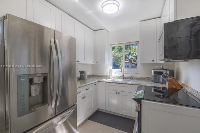 kitchen featuring stainless steel refrigerator with ice dispenser, sink, white cabinets, and light stone counters