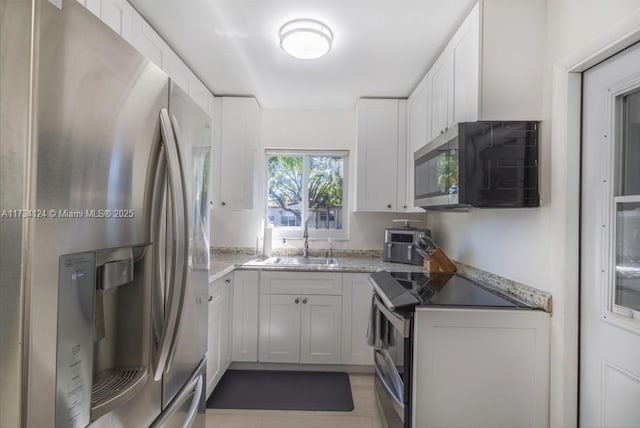 kitchen featuring stainless steel appliances, sink, dark stone countertops, and white cabinets