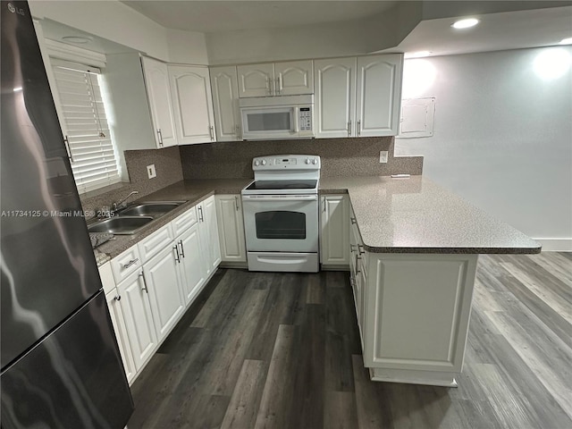 kitchen with sink, white appliances, kitchen peninsula, and white cabinets