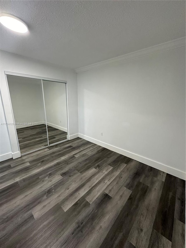 unfurnished bedroom featuring dark wood-type flooring, ornamental molding, a closet, and a textured ceiling