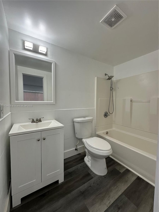 full bathroom featuring tub / shower combination, tile walls, vanity, wood-type flooring, and toilet