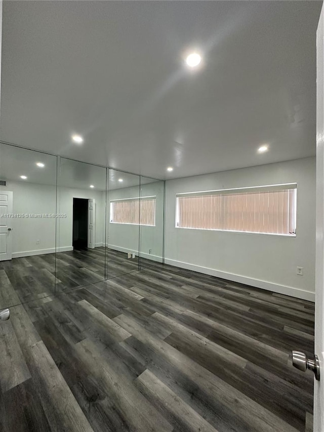 empty room with dark hardwood / wood-style flooring and a healthy amount of sunlight