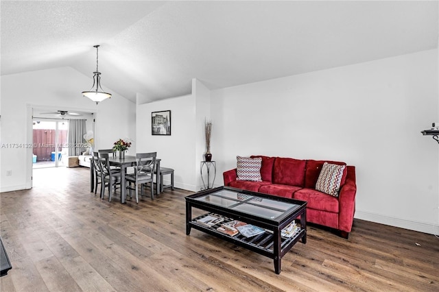 living room featuring a textured ceiling, baseboards, vaulted ceiling, and wood finished floors