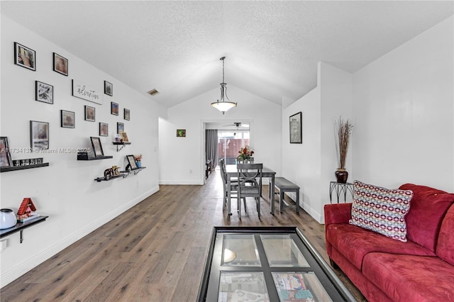 living room featuring a textured ceiling, visible vents, vaulted ceiling, and wood finished floors