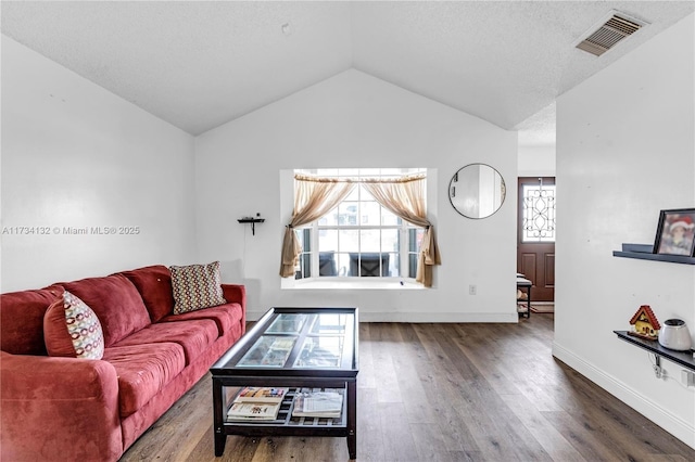 living area featuring baseboards, visible vents, wood finished floors, vaulted ceiling, and a textured ceiling