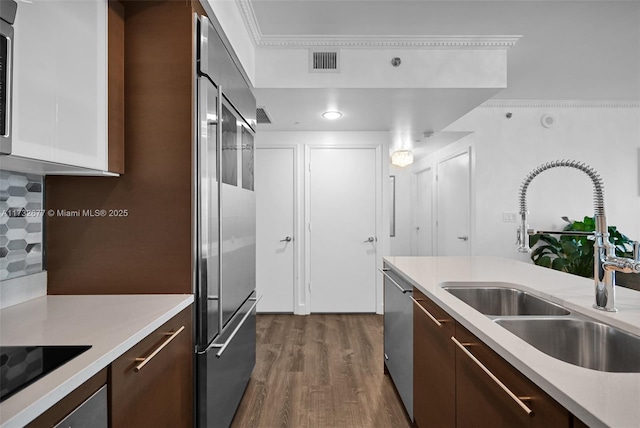 kitchen featuring dark wood-type flooring, dark brown cabinetry, sink, appliances with stainless steel finishes, and white cabinets