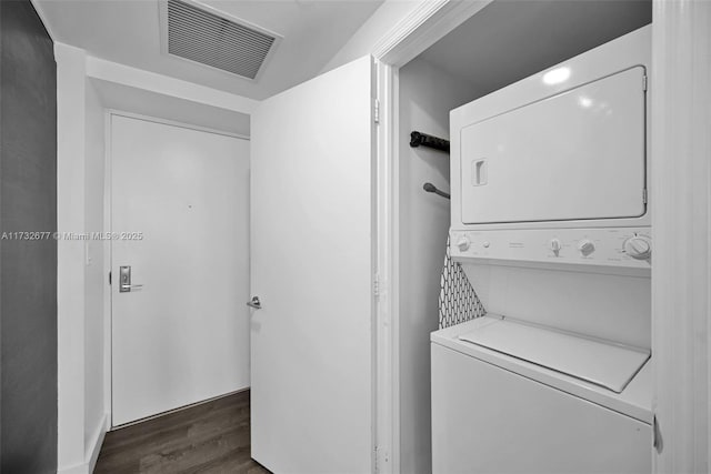 clothes washing area featuring stacked washer / drying machine and dark hardwood / wood-style floors