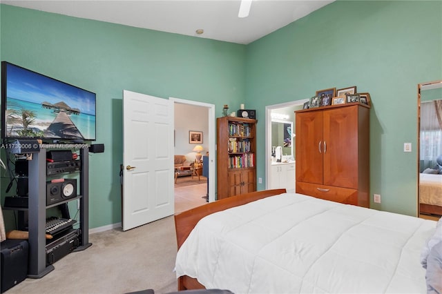 bedroom with light carpet, ensuite bath, and ceiling fan