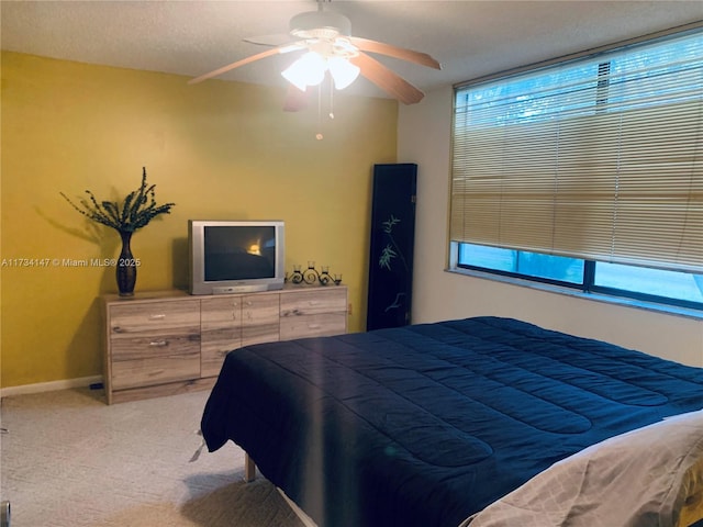 bedroom featuring ceiling fan, carpet floors, multiple windows, and a textured ceiling