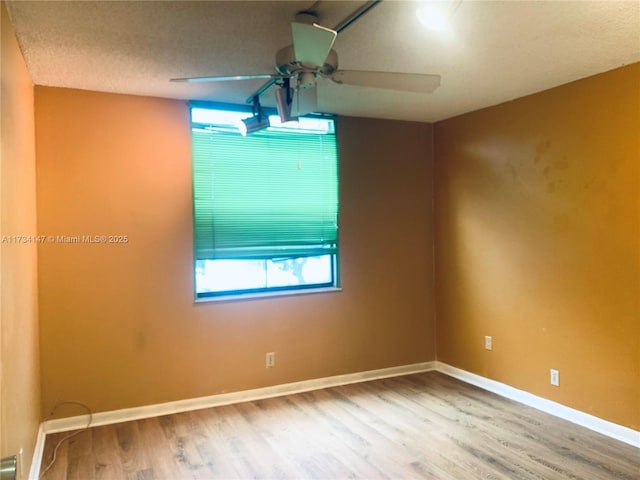 empty room with ceiling fan, wood-type flooring, and a textured ceiling