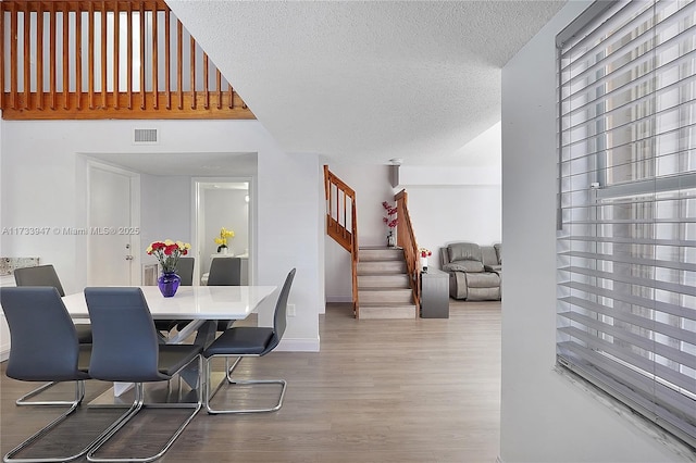 dining space with hardwood / wood-style floors and a textured ceiling