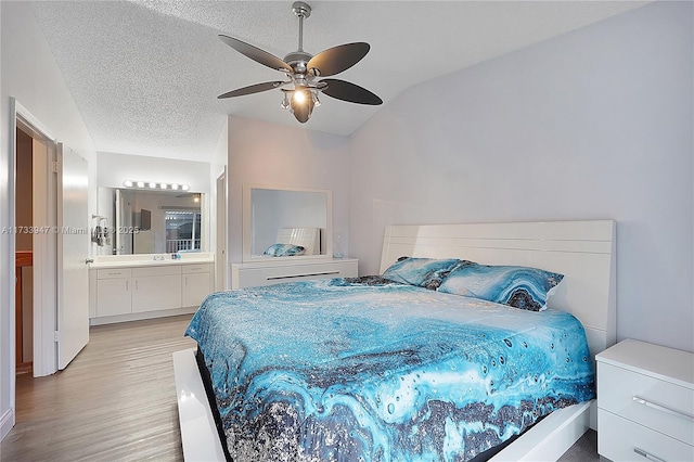 bedroom featuring ensuite bathroom, lofted ceiling, light wood-type flooring, and ceiling fan