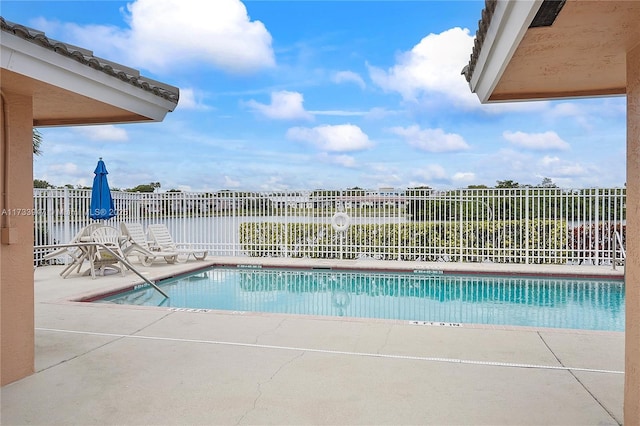 view of swimming pool with a patio area and a water view