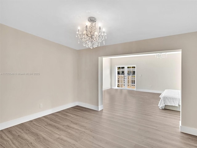 unfurnished room featuring french doors, a chandelier, and light hardwood / wood-style floors