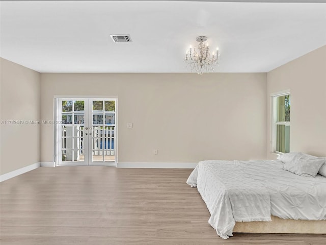 bedroom featuring an inviting chandelier, access to exterior, light hardwood / wood-style floors, and french doors