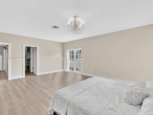 bedroom with a spacious closet, a notable chandelier, and light hardwood / wood-style flooring