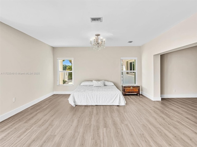 unfurnished bedroom with a notable chandelier and light wood-type flooring