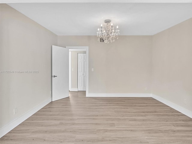 spare room featuring a notable chandelier and light hardwood / wood-style floors