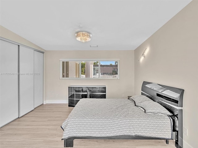 bedroom with light hardwood / wood-style floors and a closet