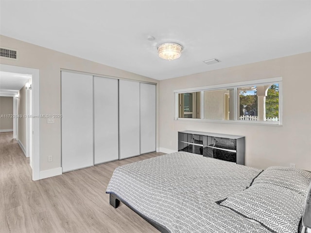 bedroom featuring lofted ceiling, light wood-type flooring, and a closet