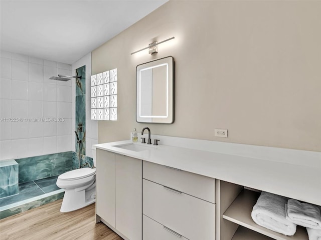 bathroom featuring vanity, toilet, hardwood / wood-style floors, and a tile shower