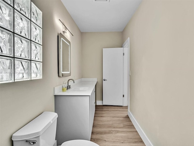 bathroom featuring vanity, wood-type flooring, and toilet