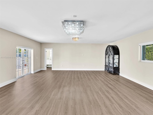 unfurnished living room with hardwood / wood-style flooring, a chandelier, and a healthy amount of sunlight