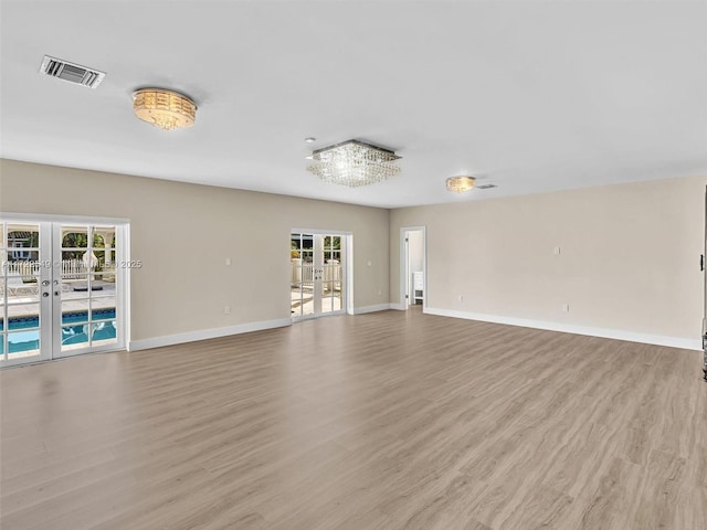 12904 Banyan Rd, North Miami, FL 33181 - unfurnished living room with french doors, light wood-style floors, and baseboards