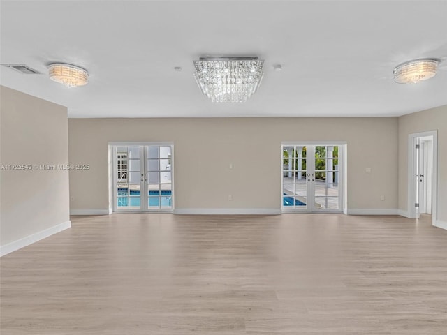 spare room with french doors and light hardwood / wood-style floors