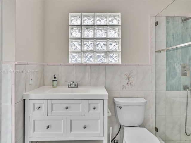 bathroom with vanity, tile walls, toilet, and walk in shower