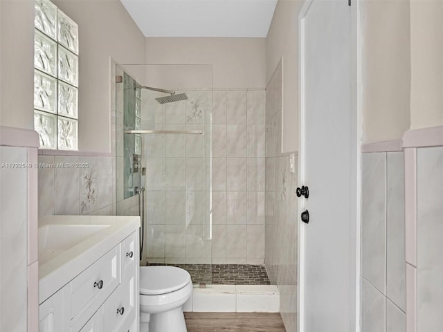 bathroom featuring walk in shower, vanity, and tile walls