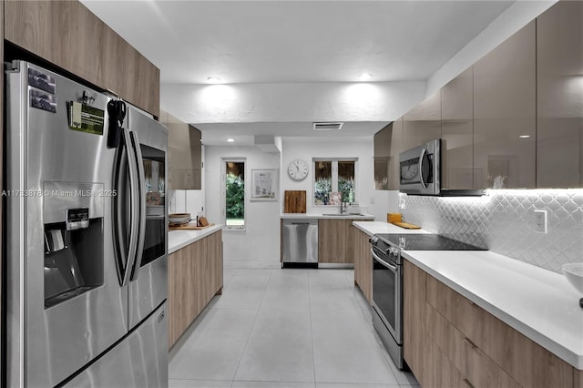 kitchen featuring tasteful backsplash, appliances with stainless steel finishes, sink, and light tile patterned floors