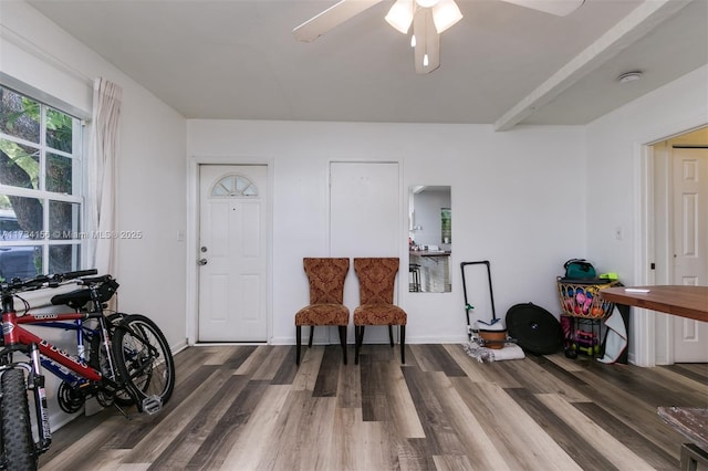 sitting room with wood-type flooring, beamed ceiling, and ceiling fan