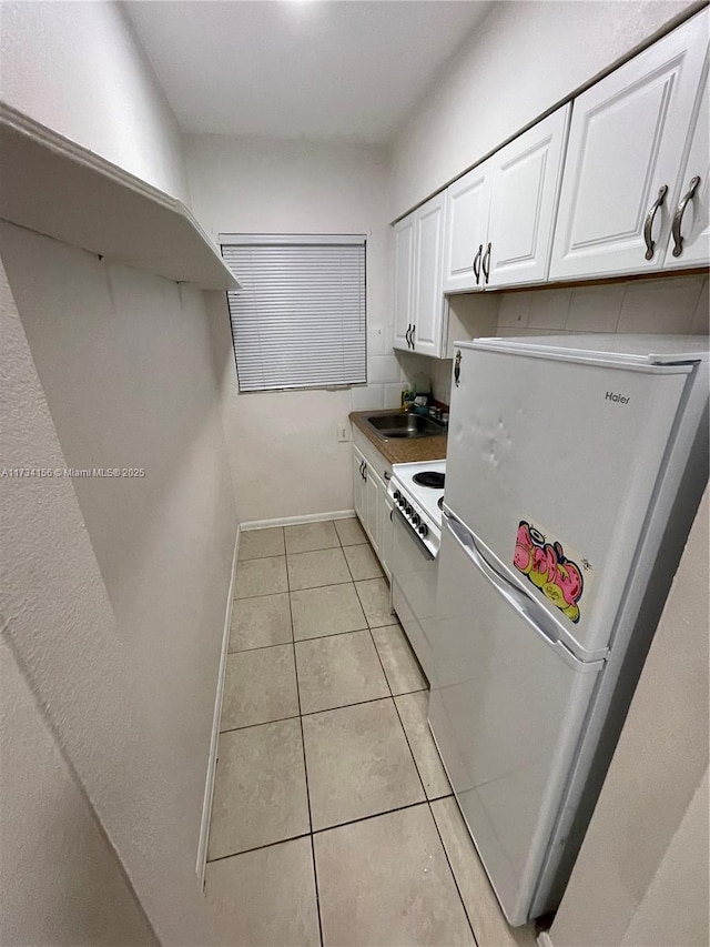 kitchen with white electric range, sink, white cabinets, fridge, and light tile patterned floors