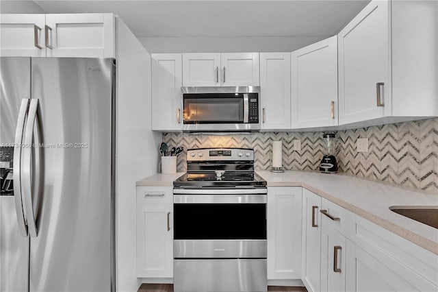 kitchen with tasteful backsplash, white cabinetry, stainless steel appliances, and light stone counters