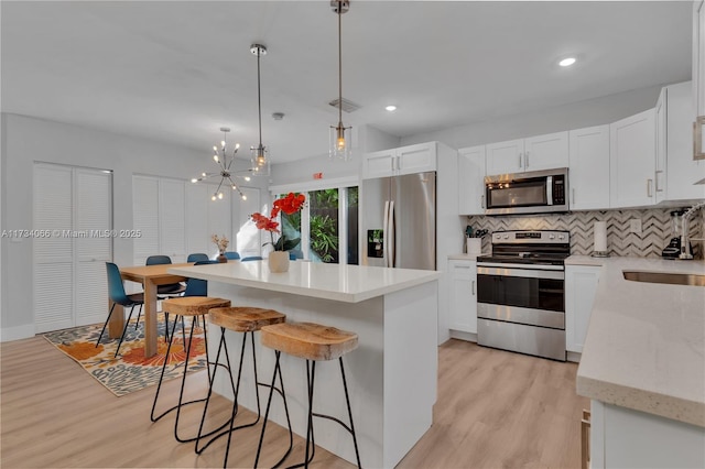 kitchen featuring pendant lighting, tasteful backsplash, white cabinetry, a center island, and stainless steel appliances