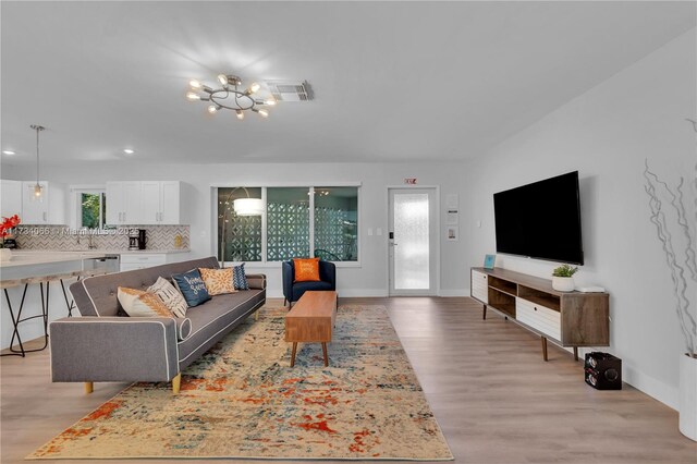 living room with a healthy amount of sunlight, light hardwood / wood-style flooring, and a notable chandelier