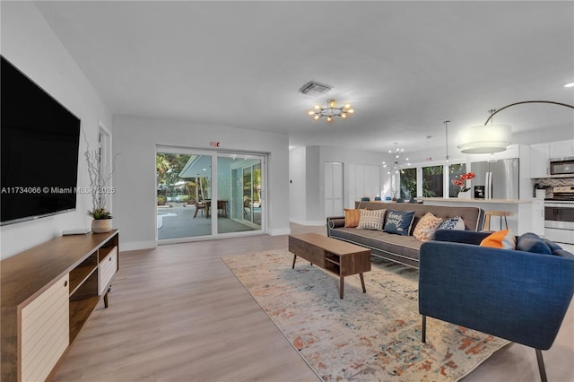 living room with light hardwood / wood-style floors and a notable chandelier