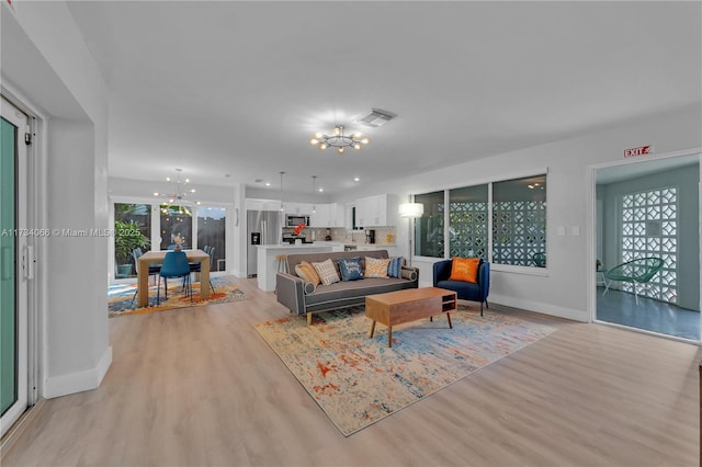 living room with a notable chandelier and light hardwood / wood-style flooring