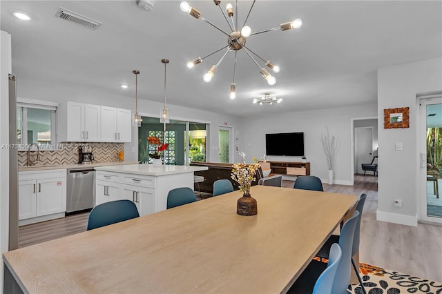 dining room with sink, a notable chandelier, and light hardwood / wood-style floors