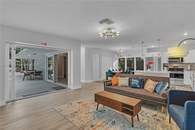 living room featuring a healthy amount of sunlight, a chandelier, and light hardwood / wood-style flooring