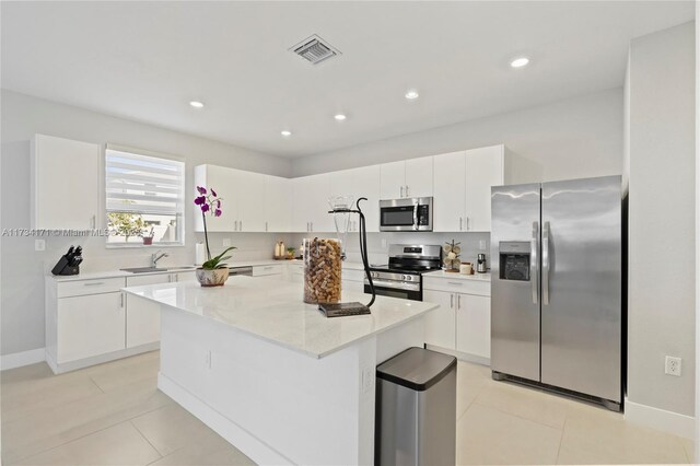 kitchen with stainless steel appliances, a center island, sink, and white cabinets