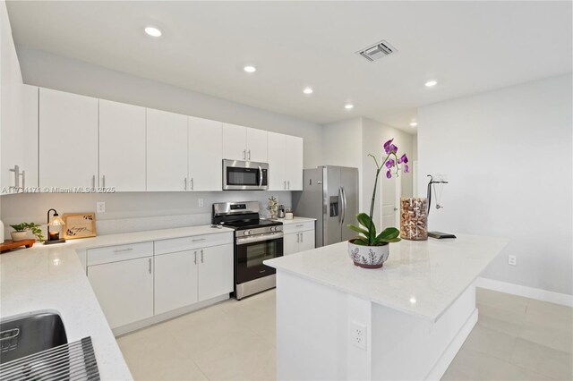 14823 SW 163rd Ter, Miami, FL 33187 - kitchen with stainless steel appliances, a center island, white cabinetry, light tile patterned flooring, and recessed lighting