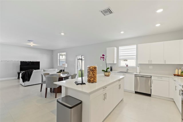 kitchen with sink, stainless steel dishwasher, white cabinets, and a kitchen island